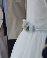 Detalle de la colección de La Cuna Comuniones: vestido de comunión con fajín de flores y trajes de marinero y almirante